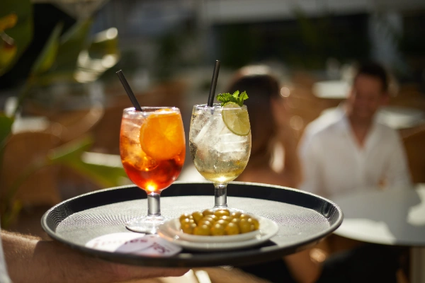 Dos c&oacute;cteles y un plato de aceitunas se sirven en una terraza.