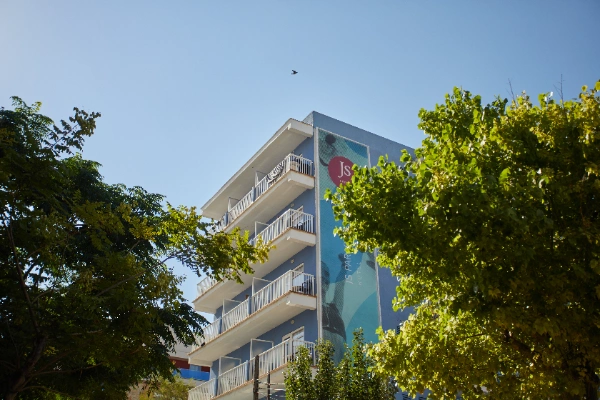 Edificio de varios pisos rodeado de &aacute;rboles bajo un cielo despejado.