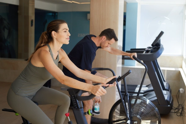 Personas ejercit&aacute;ndose en bicicletas est&aacute;ticas en un gimnasio.