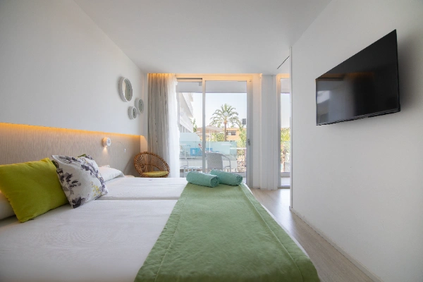 Habitaci&oacute;n moderna con cama doble, televisor y ventana con vista exterior.