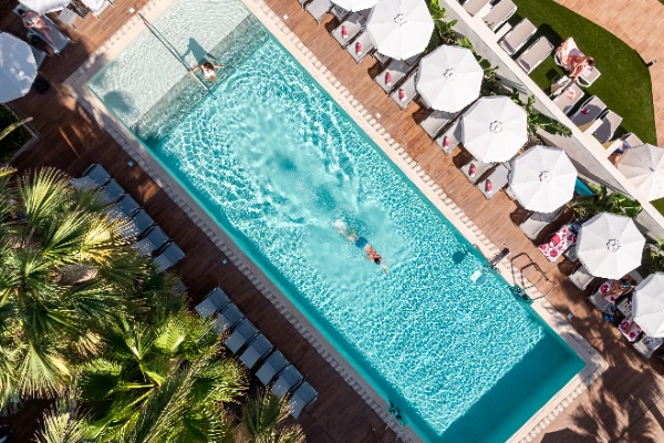 Piscina al aire libre con sombrillas y tumbonas alrededor.
