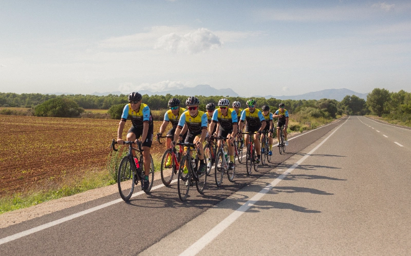 Grupo de ciclistas en carretera rural bajo un cielo despejado.