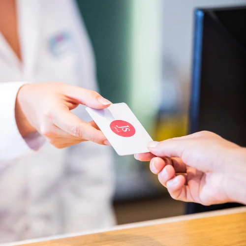 Manos intercambiando una tarjeta blanca con un logo rojo.