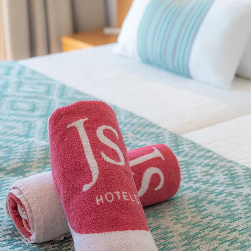 Toallas rosas sobre cama en habitaci&oacute;n de hotel.