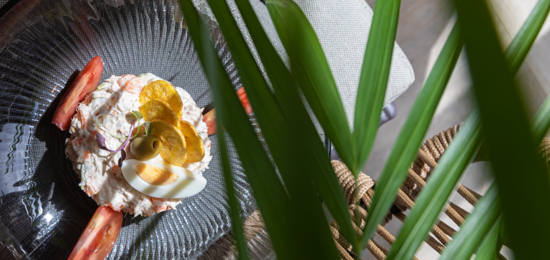 Ensalada con huevo, aceituna y decoraci&oacute;n verde en plato de vidrio.