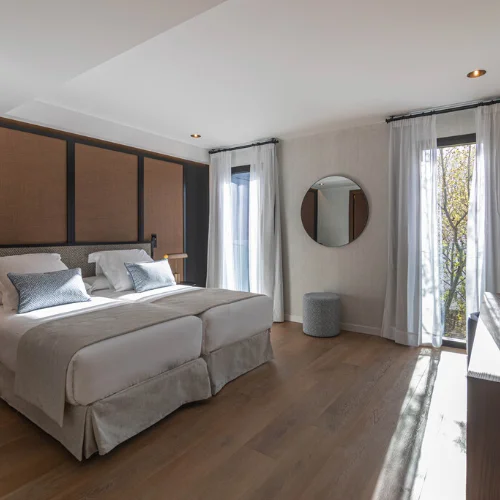 Habitaci&oacute;n moderna con cama doble, ventanales y decoraci&oacute;n minimalista.