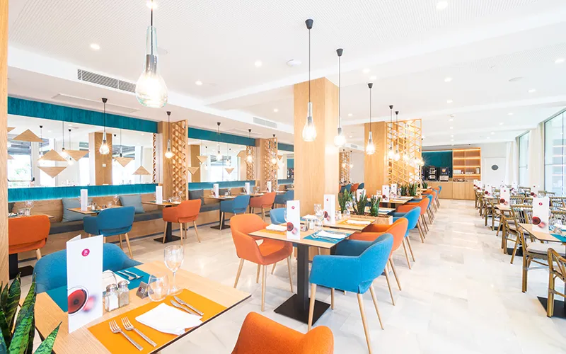 Restaurante moderno con sillas de colores y mesas elegantemente dispuestas.