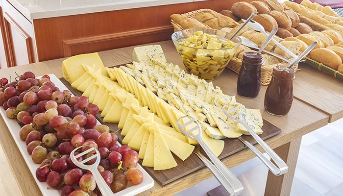 Mesa con uvas, quesos, pan, mermeladas y aceitunas.