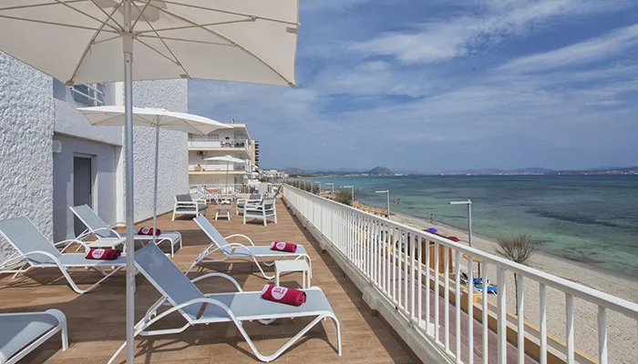 Terraza con tumbonas y vista al mar bajo un cielo despejado.