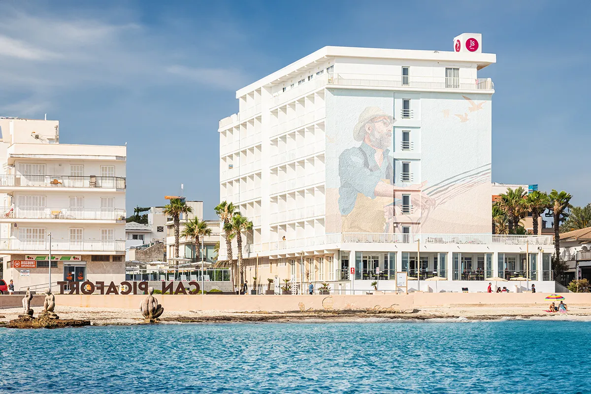 Edificio blanco en la playa con mural y cielo despejado.