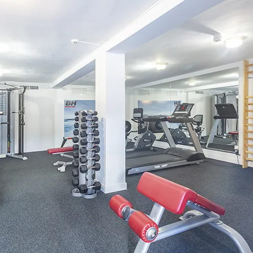 Gimnasio con cintas de correr, pesas y equipo de entrenamiento.