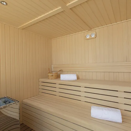 Sauna de madera con toallas enrolladas sobre la banca.
