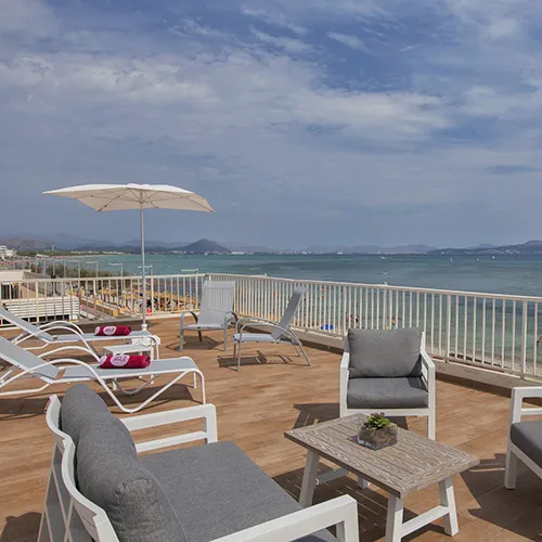Terraza frente al mar con sillones, sombrilla y vistas al oc&eacute;ano.