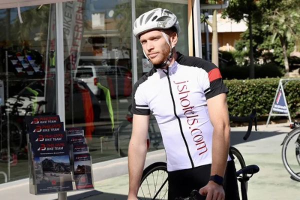 Ciclista con casco en la calle junto a una bicicleta.