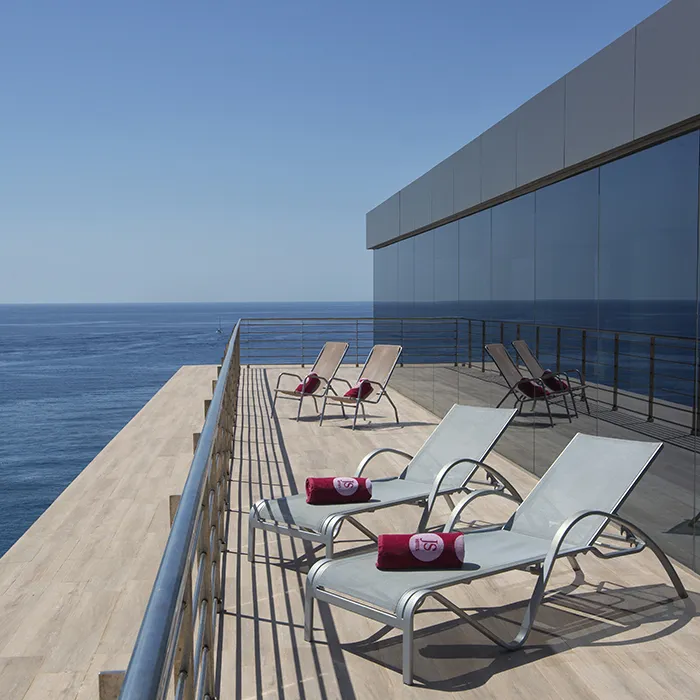 Terraza con tumbonas y vista al mar en un d&iacute;a soleado.