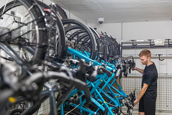 Persona organizando bicicletas en un estacionamiento interior.