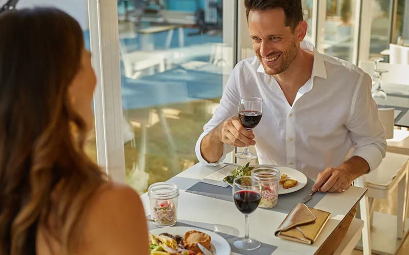 Pareja sonriendo mientras cena en un restaurante luminoso.