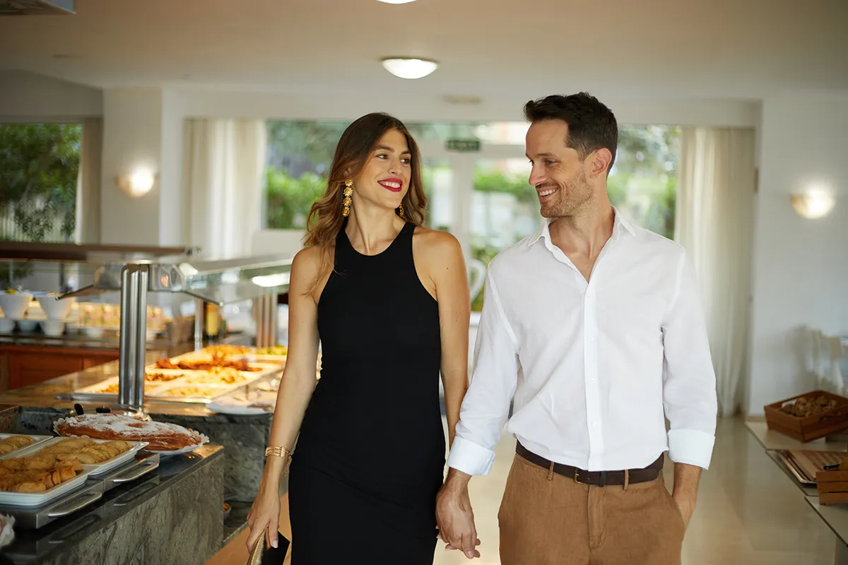 Pareja sonriente caminando junta en un buffet.