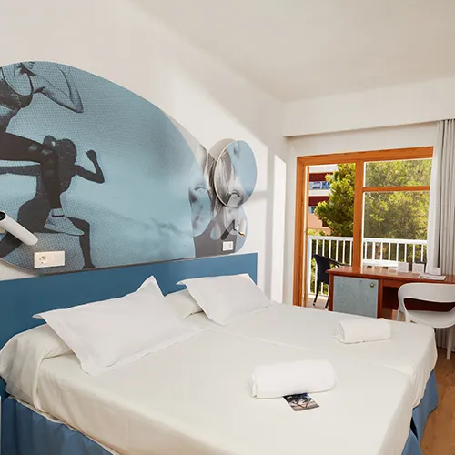 Habitaci&oacute;n moderna con decoraci&oacute;n deportiva, cama doble y ventana con vista al jard&iacute;n.