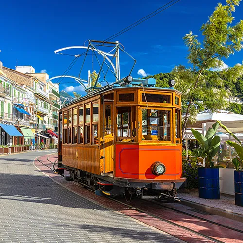 Tranv&iacute;a vintage en una colorida calle con cielo despejado.