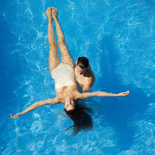 Dos personas flotan en una piscina, una mujer apoyada sobre un hombre.