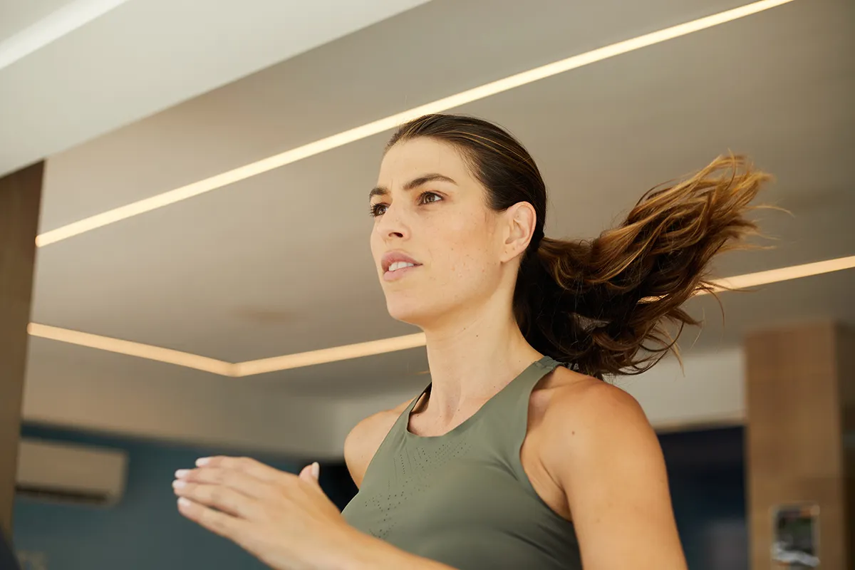 Mujer corriendo en interior con expresi&oacute;n de concentraci&oacute;n.