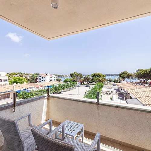 Balc&oacute;n con vista al mar y sillas de mimbre bajo un cielo despejado.