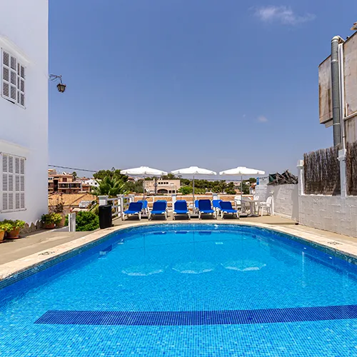 Piscina al aire libre con tumbonas y sombrillas bajo un cielo despejado.