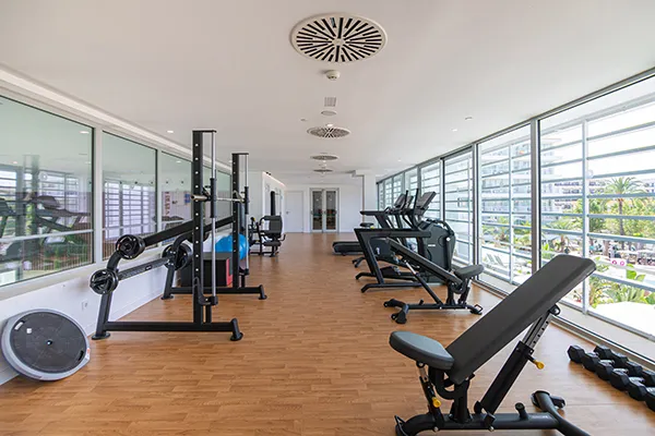 Gimnasio moderno con equipo de ejercicio y ventanas amplias.