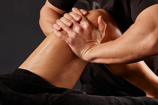 Masaje de piernas con manos presionando la pierna de una persona.