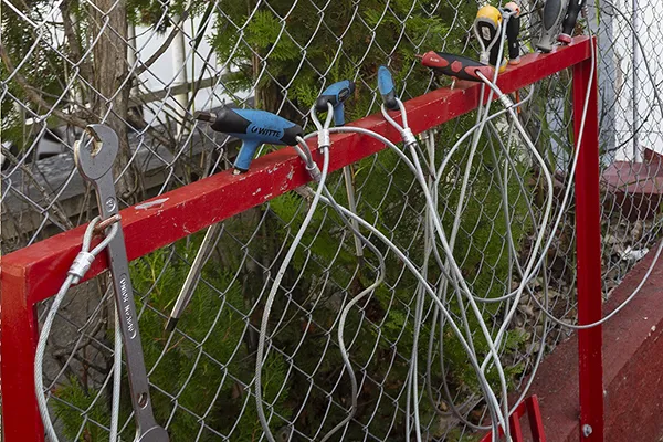 Herramientas colgadas en una estructura roja, frente a una reja met&aacute;lica.