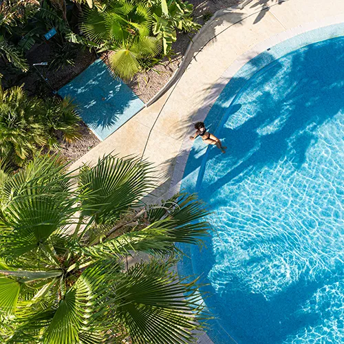 Vista a&eacute;rea de una piscina con una persona nadando y &aacute;rboles alrededor.
