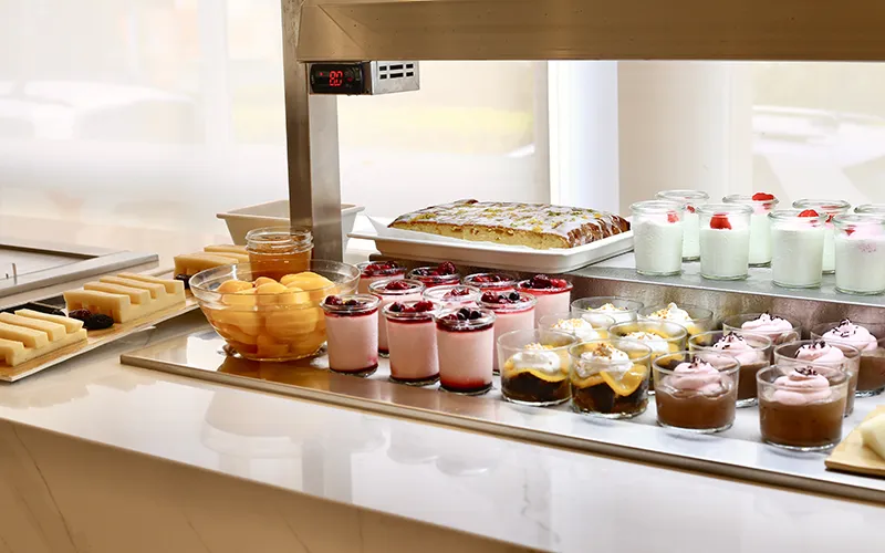 Postres variados en una vitrina de buffet, como tartas y gelatinas.