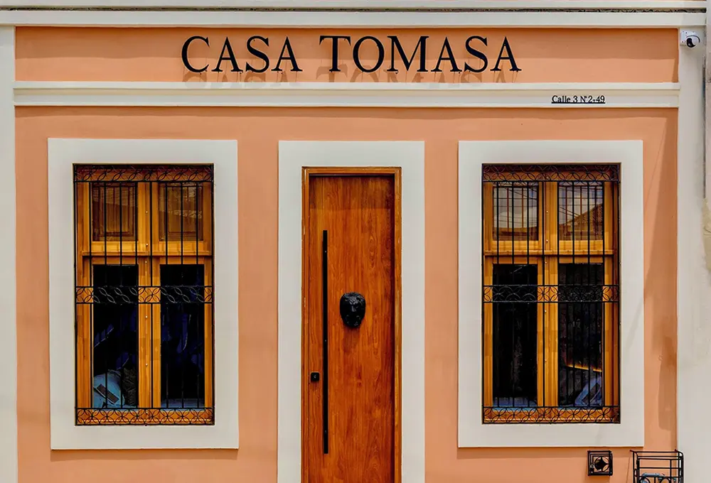 Fachada de Casa Tomasa con puerta y ventanas de madera.