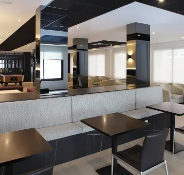 Área de descanso moderna con mesas, sillas y decoración elegante en tonos neutros.