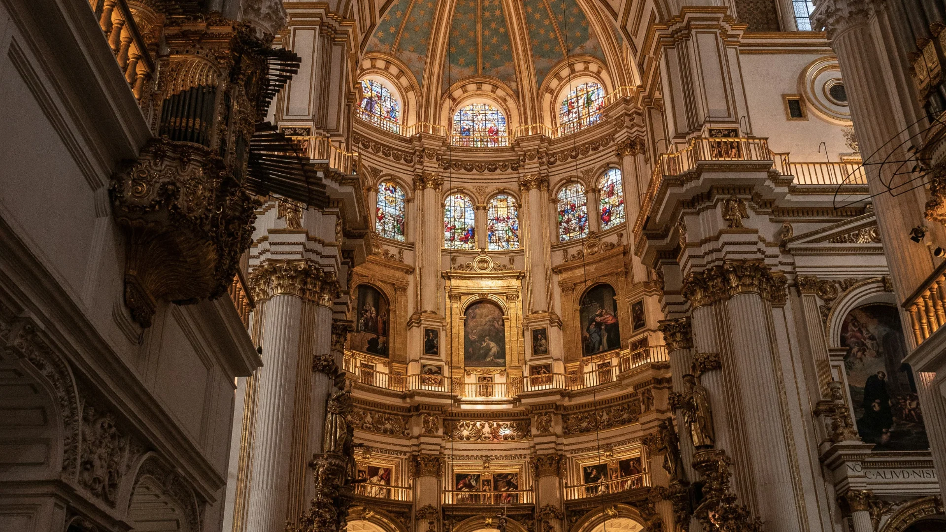 Interior de catedral barroca con vitrales y &oacute;rgano ornamentado.