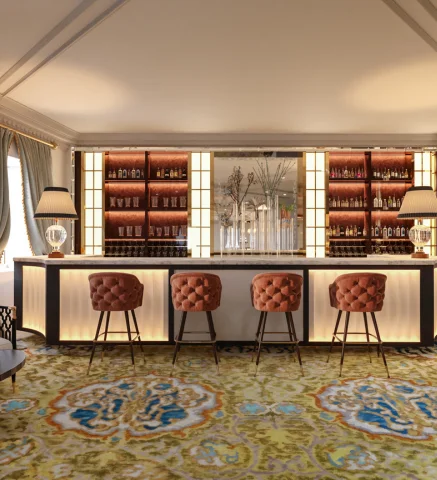 Bar elegante con taburetes y paredes iluminadas por detr&aacute;s.