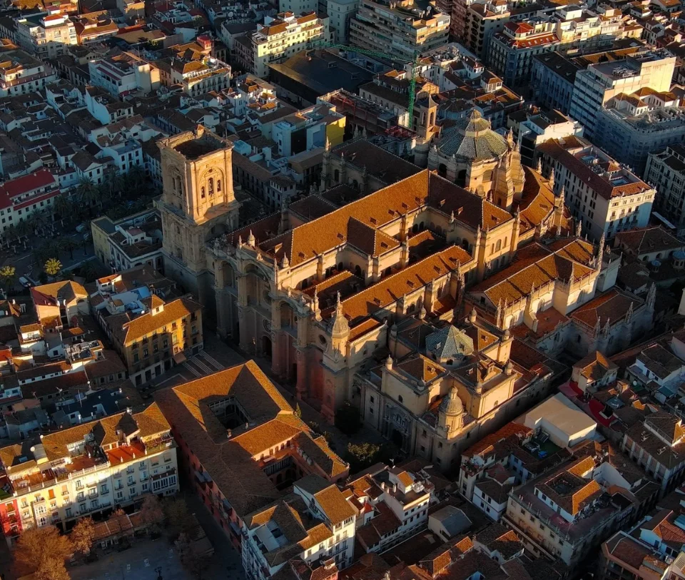 Vista a&eacute;rea de una catedral rodeada de edificios en el atardecer.