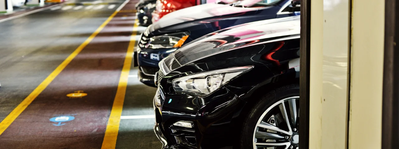 Coches estacionados en fila en un garaje con l&iacute;neas amarillas en el suelo.