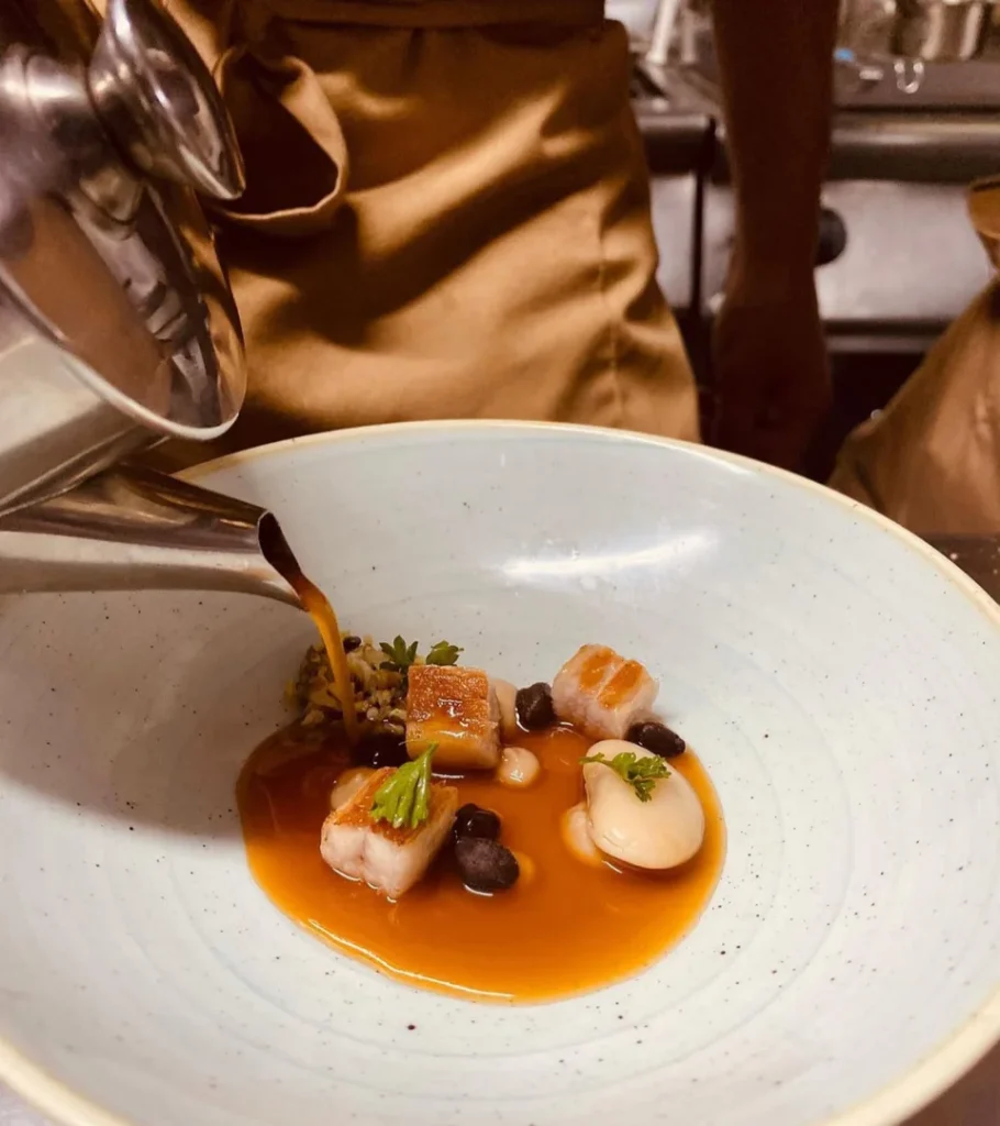 Plato gourmet con carne, salsa y decoraci&oacute;n en la cocina de un restaurante.