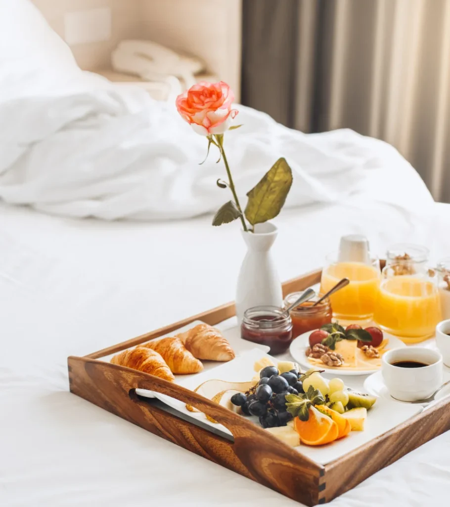 Desayuno en cama con flores y bandeja de madera.