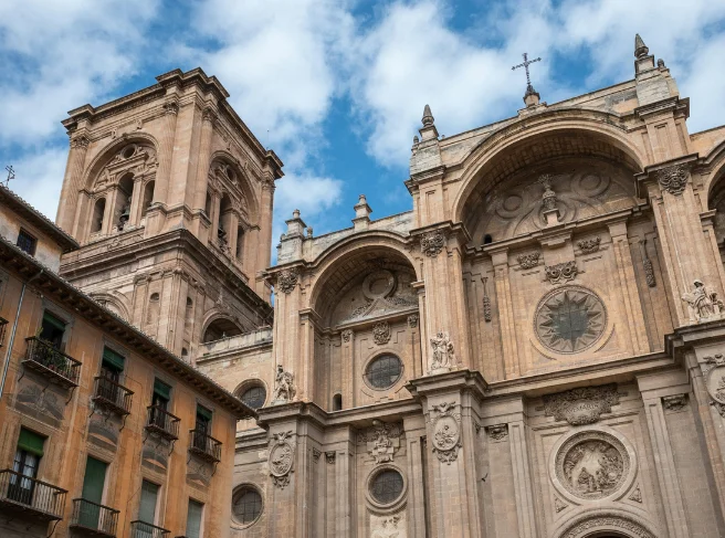 Fachada de una catedral antigua con cielo azul y nubes.