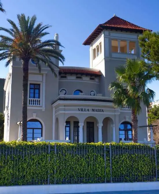 Edificio "Villa Maria" con palmeras y cielo azul.