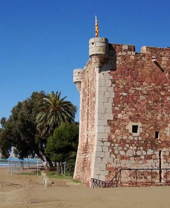 Castillo de ladrillo rojo y árbol bajo un cielo azul diáfano.