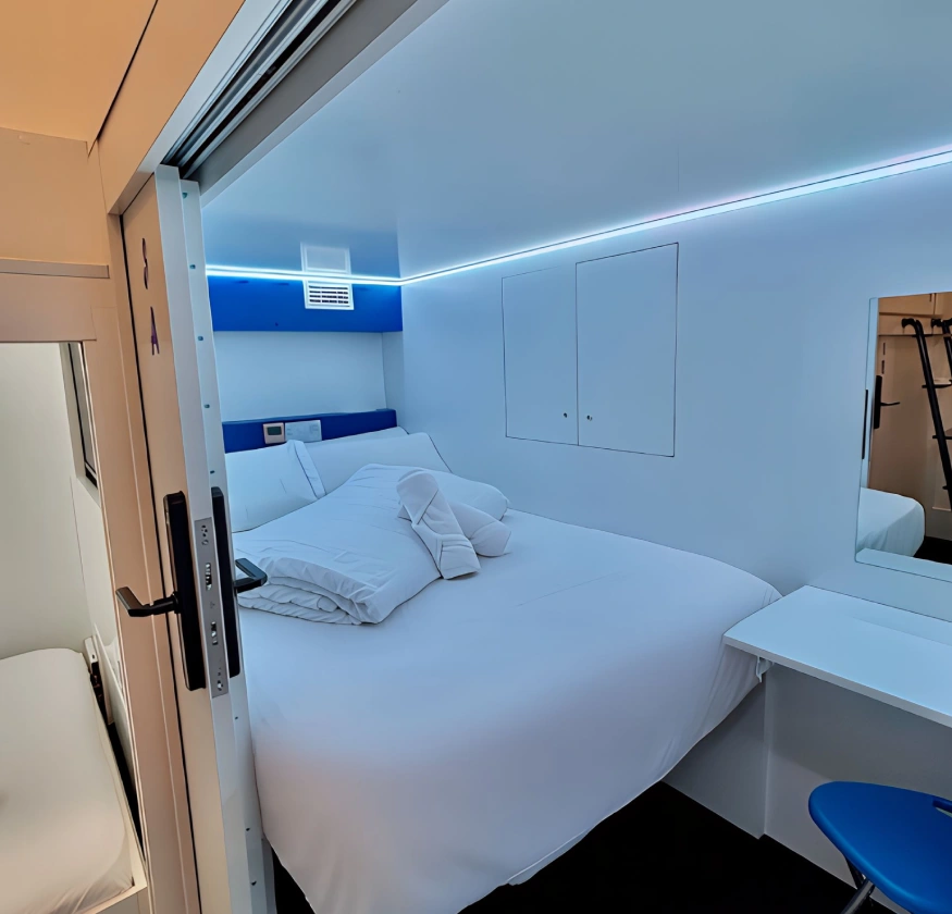 Habitaci&oacute;n peque&ntilde;a y moderna con cama doble y luces LED azules.