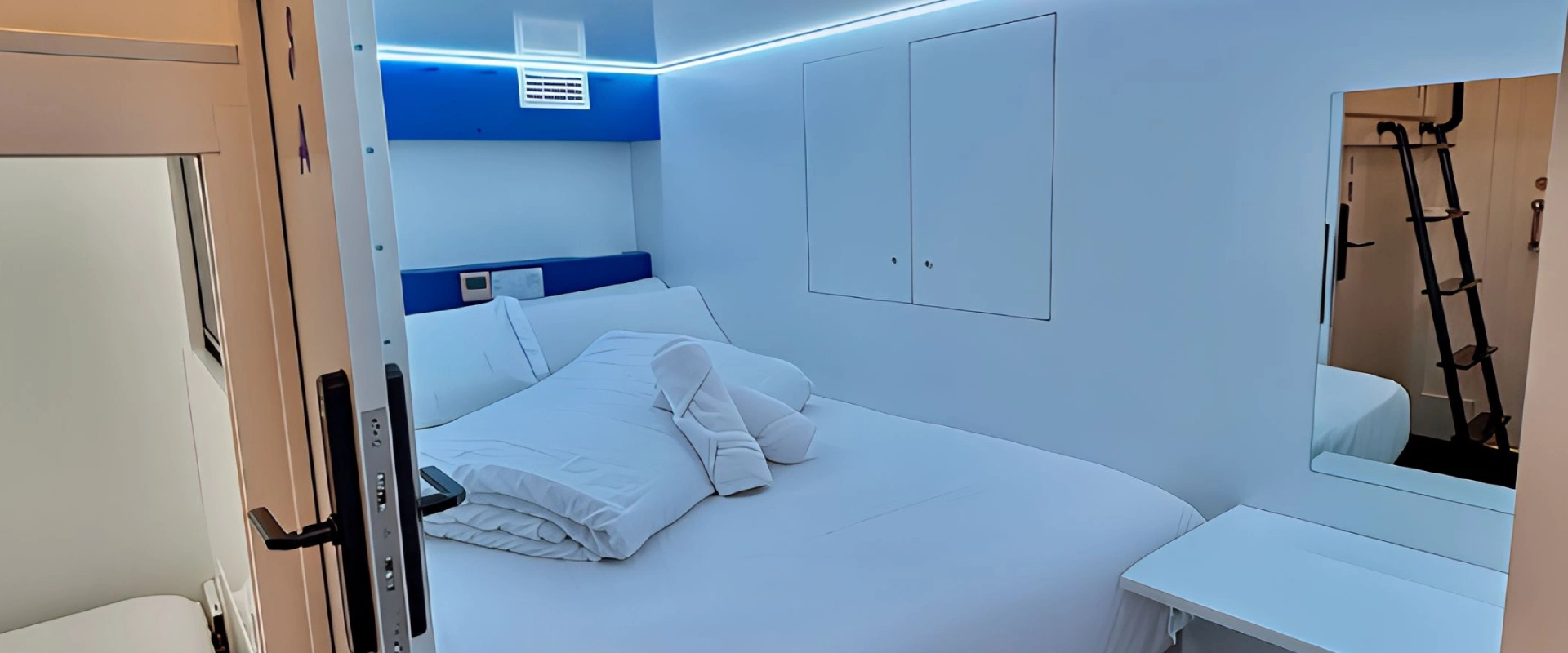 Cama en una habitaci&oacute;n moderna con luz azul y espejo.