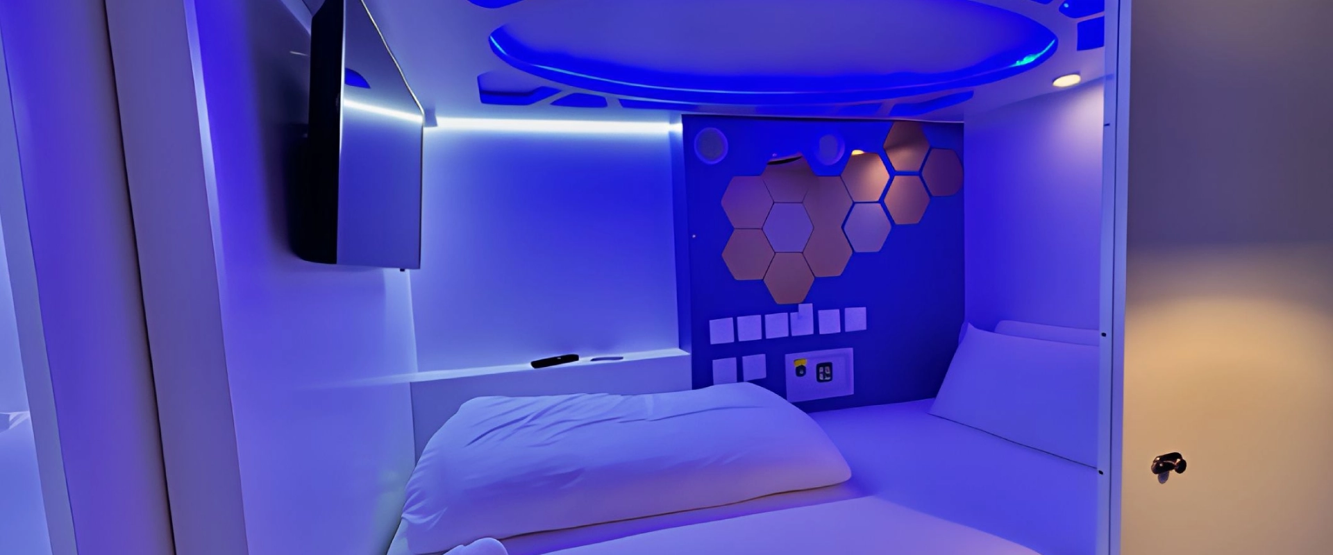 Habitaci&oacute;n futurista con iluminaci&oacute;n azul y dise&ntilde;o de panales hexagonales en la pared.