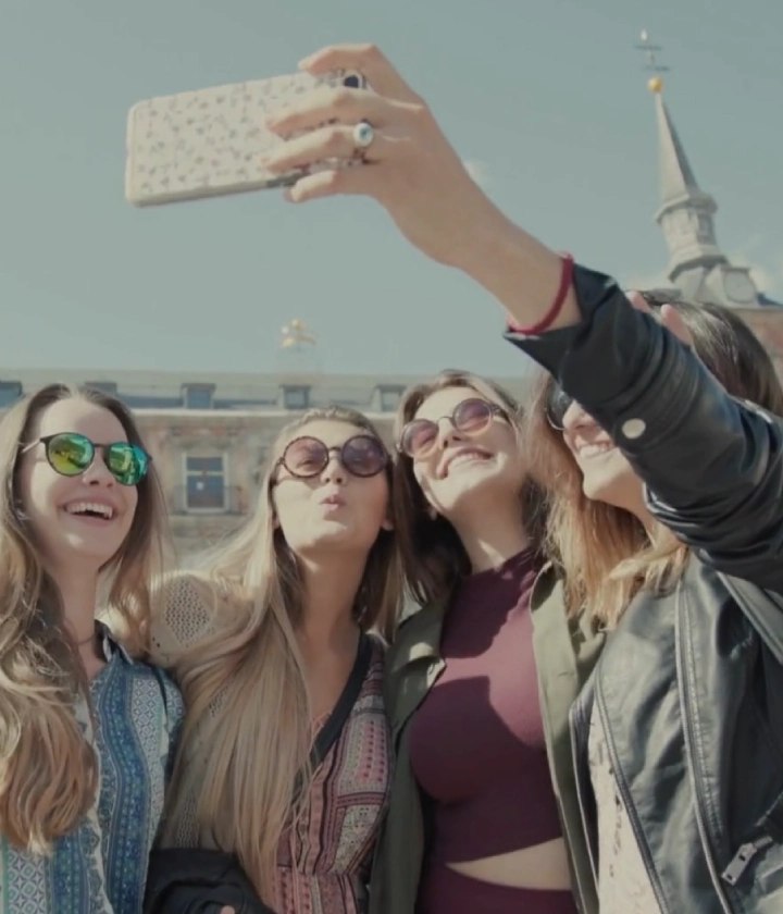Cuatro personas sonriendo y sac&aacute;ndose una selfie al aire libre en un d&iacute;a soleado.