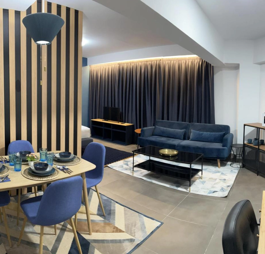 Sala moderna con sof&aacute; azul, comedor y decoraci&oacute;n elegante. Pared de madera a rayas.