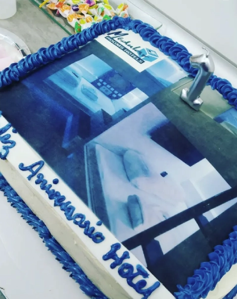 Pastel con decoraci&oacute;n azul, foto de hotel y el texto "13&deg; Aniversario Hotel". N&uacute;mero 1 plateado.